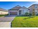 Single-story home with a brown door and garage door, and nicely landscaped lawn at 14281 17Th E Ct, Parrish, FL 34219