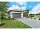 Two-car garage, paver driveway, and landscaped lawn with lush greenery at 15910 Clear Skies Pl, Bradenton, FL 34211