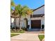 White house with brown garage door, palm trees, and landscaped lawn at 17322 Holly Well Ave, Wimauma, FL 33598