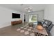 Spacious living room with hardwood floors, gray couch, and large TV at 17322 Holly Well Ave, Wimauma, FL 33598