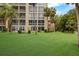 Backyard view of apartment building with lush green lawn and tropical trees at 3544 Lake Bayshore Dr # K123, Bradenton, FL 34205