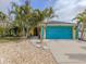 Yellow house with teal garage door and tropical landscaping at 3972 Titan St, North Port, FL 34286