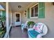 Inviting front porch with white wicker chairs and teal cushions at 5708 Miami Rd, Venice, FL 34293