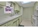 Efficient kitchen with light green cabinets, white appliances, and a window at 5708 Miami Rd, Venice, FL 34293