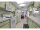 Kitchen boasts light green cabinets, white appliances, and dining area view at 5708 Miami Rd, Venice, FL 34293