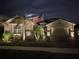 Two-story house with a landscaped yard, a flag, and a paved driveway at night at 20296 Bandera Pl, Venice, FL 34293