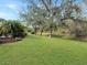 Landscaped backyard with mature trees and grassy area at 25072 Palisade Rd, Punta Gorda, FL 33983
