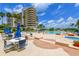 Exterior of building featuring pool, hot tub and lounge area with bright blue sky and palm trees at 3080 Grand Bay Blvd # 521, Longboat Key, FL 34228