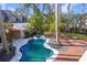Elevated view of a freeform pool, spa, and brick patio with tropical landscaping at 320 29Th Nw St, Bradenton, FL 34205
