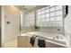 Bathroom with a shower, soaking tub, and a large glass block window at 5401 Oak Grove Ct, Sarasota, FL 34233
