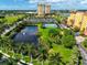 Aerial view of community features including a pond, tennis courts, and resort-style buildings at 615 Riviera Dunes Way # 104, Palmetto, FL 34221