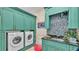 Laundry room with green cabinets, a utility sink, and a stackable washer and dryer at 635 Key Royale Dr, Holmes Beach, FL 34217