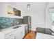 Updated kitchen with white cabinets, stainless steel appliances, and tile backsplash at 800 S Blvd Of Presidents # 12, Sarasota, FL 34236