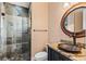 Bathroom featuring a walk-in tiled shower, unique vessel sink, and decorative mirror at 8388 Catamaran Cir, Lakewood Ranch, FL 34202