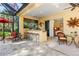 Outdoor kitchen with bar seating and adjacent patio furniture at 8808 Enclave Ct, Sarasota, FL 34238