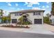 Two-story house with a light-colored facade, two-car garage, and tropical landscaping at 127 Crescent Dr, Anna Maria, FL 34216