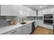 White kitchen with gray tile backsplash and stainless steel appliances at 127 Crescent Dr, Anna Maria, FL 34216