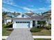 White house with light blue garage door, paver driveway, and landscaping at 13153 Steinhatchee Loop, Venice, FL 34293