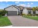 Two-story home with gray exterior, landscaping, and paver driveway at 2028 Woodleaf Hammock Ct, Bradenton, FL 34211