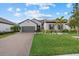 Single-story home with a gray exterior, landscaping, and paver driveway at 2028 Woodleaf Hammock Ct, Bradenton, FL 34211