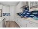 White kitchen with blue and green tile backsplash and stainless steel appliances at 2028 Woodleaf Hammock Ct, Bradenton, FL 34211