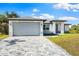 New single-story home with gray garage door and paver driveway at 2133 Selover Rd, North Port, FL 34287