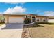 Tan house with white garage door and landscaping at 22419 Bette Ave, Port Charlotte, FL 33954