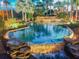 Evening view of resort-style pool with waterfall and lush landscaping at 314 Mystic Falls Dr, Apollo Beach, FL 33572