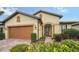 Tan house with orange garage door, lush landscaping, and a paved driveway at 5552 Eagle Creek Rd, Sarasota, FL 34238