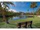 Park pond with fountain and bench under sunny sky at 713 Saint Judes S Dr # 2, Longboat Key, FL 34228