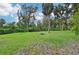 Lush green backyard with fire pit, surrounded by trees at 1702 Spoonbill Dr, Nokomis, FL 34275