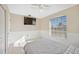 Well-lit bedroom featuring a ceiling fan, mounted television, and large window at 1817 New London St, North Port, FL 34288