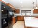 Kitchen with granite counters, wood cabinets and black appliances at 19261 Isadora St, Venice, FL 34293