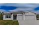 One-story house with gray siding, three-car garage, and a well-manicured lawn at 22490 Madelyn Ave, Port Charlotte, FL 33954