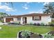 Charming single-story home featuring a manicured lawn, colorful flower beds, and a cozy, inviting entryway at 320 Whitfield Ave, Sarasota, FL 34243