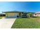 Single-story house with green exterior, attached garage, and well-maintained lawn at 5 Pinehurst Ct, Rotonda West, FL 33947