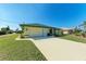 House exterior showcasing a beige and green color scheme, a garage, and a neat lawn at 5 Pinehurst Ct, Rotonda West, FL 33947