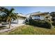 Light-grey house exterior with lush green hedges and palm tree at 1003 Lake Avoca Dr, Tarpon Springs, FL 34689