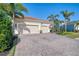 Three-car garage with paver driveway and tropical landscaping at 12654 Harney St, Venice, FL 34293