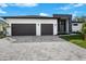 Modern two-car garage home with gray paver driveway and landscaping at 13377 Alocasia Ln, Port Charlotte, FL 33981