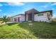 Contemporary house with two-car garage, and lush green landscaping at 13377 Alocasia Ln, Port Charlotte, FL 33981