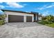 Modern home with two-car garage, gray paver driveway, and green lawn at 13377 Alocasia Ln, Port Charlotte, FL 33981