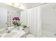 Bathroom with white tile, a shower/tub combo, and decorative orchids at 1602 Stickney Point Rd # 1602-301, Sarasota, FL 34231