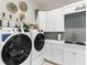 Bright laundry room with modern washer and dryer, white cabinets, and gray tile at 3354 Founders Club Dr, Sarasota, FL 34240