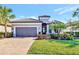 Single-story home with gray garage door, lush landscaping, and brick driveway at 4020 Cascina Way, Sarasota, FL 34238