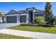 Two-story house with gray exterior, three-car garage, and landscaped yard at 18096 Home Run Dr, Venice, FL 34293