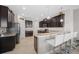 Kitchen with breakfast bar, white barstools, and dark wood cabinets at 5015 Jagged Cloud Dr, Wimauma, FL 33598