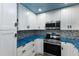 Bright kitchen with white cabinets, blue tile backsplash and stainless steel appliances at 6250 Holmes Blvd # 71, Holmes Beach, FL 34217