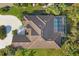 Aerial view of home with a large brown tile roof, screened-in pool area, lush landscaping, and circular driveway at 5245 88Th E St, Bradenton, FL 34211