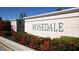 An attractive Rosedale community sign framed by vibrant red flowers and lush green foliage on a sunny day at 5245 88Th E St, Bradenton, FL 34211